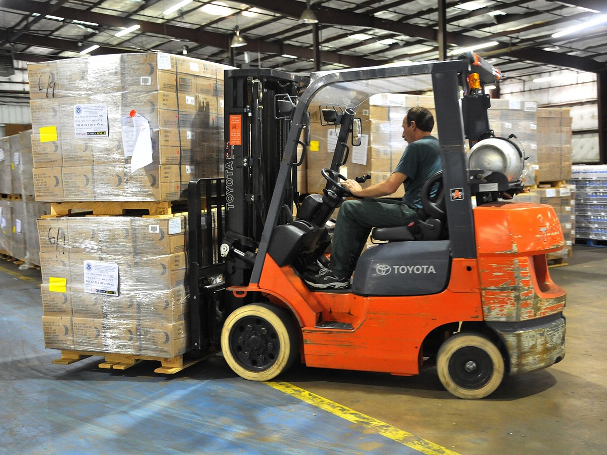 Operator lifting a load of boxed supplies with a Toyota forklift inside a warehouse