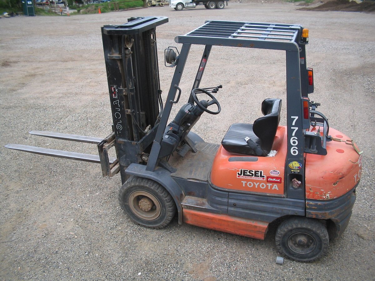 Pre-owned orange Toyota propane counterbalance forklift parked on a paved lot