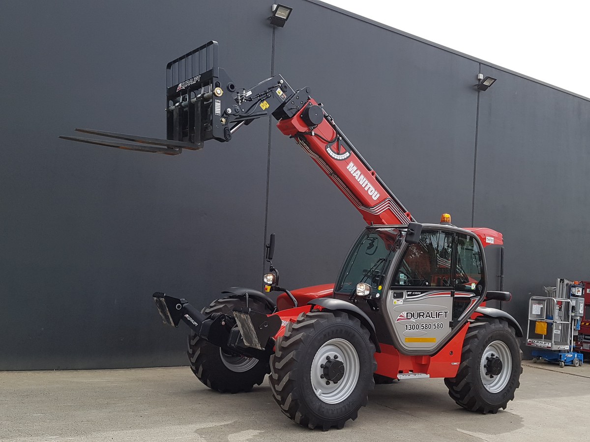 Red Manitou telescopic handler with boom extended and forks raised